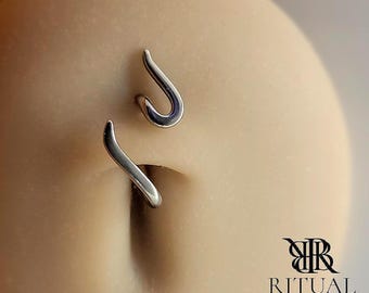 May include: A silver-toned navel piercing jewelry piece featuring two separate, smooth, curved metal components. One piece is shaped like a small hook, while the other is a longer, wavy bar. The logo for Ritual Body Jewelry is in the corner.