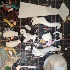 May include: White plastic model kit pieces for assembling a figure. The pieces include a head, arms, legs, hair, a base, and a flying saucer.