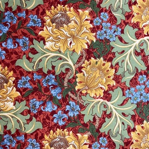 May include: A red fabric with a floral pattern. The pattern features large yellow flowers with green leaves and smaller blue flowers.