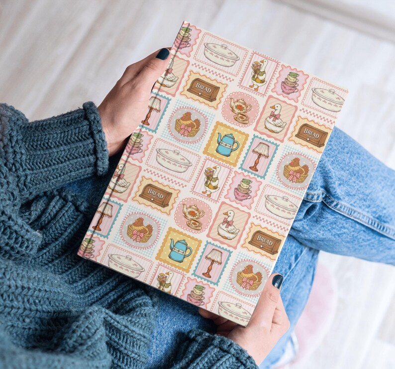 May include: A hardcover book featuring a repeating pattern of postage stamp-style illustrations. The design includes images of white geese, blue teapots, brown bread boxes labeled BREAD, pink lamps, and white casserole dishes on a light background.