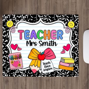 May include: A rectangular mousepad with a black and white composition notebook paper design. The mousepad features the word "TEACHER" in colorful bubble letters, the name "Mrs. Smith", and school-themed graphics like a pencil, apple, and books.