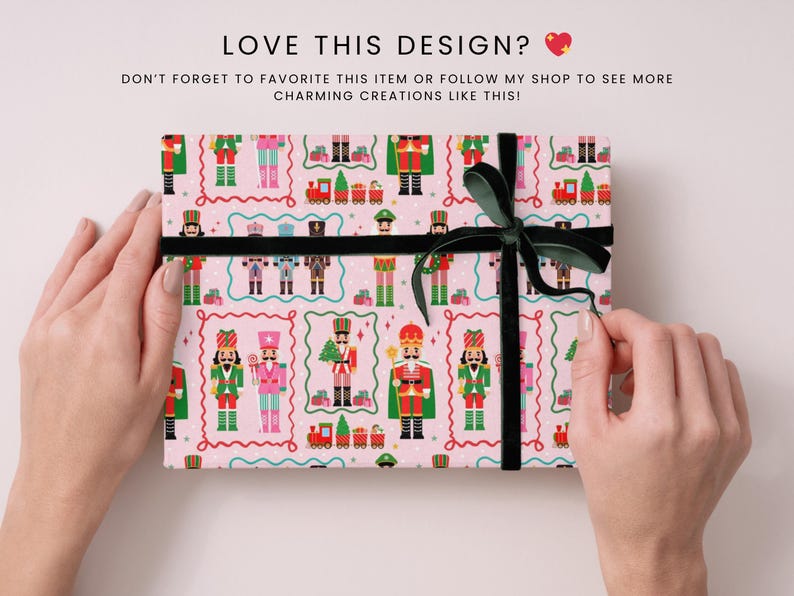 May include: A pink gift box with a repeating pattern of toy nutcracker soldiers, trains, and Christmas trees. The box is tied with a black ribbon and a dark green bow. The text "LOVE THIS DESIGN?" is at the top.