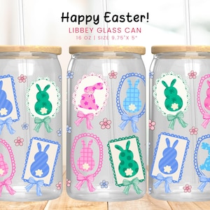 Puede incluir: Tres latas de vidrio transparente con tapas de madera, cada una adornada con diseños de conejitos de Pascua en rosa, verde y azul. Las latas presentan el texto "Happy Easter!" y miden 24,77 cm x 12,7 cm.