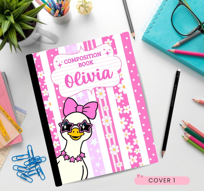 May include: A composition book with a pink and white striped cover featuring a white duck wearing a pink bow and star-shaped sunglasses. The cover displays the text "COMPOSITION BOOK" and the name "Olivia" in a decorative white label.