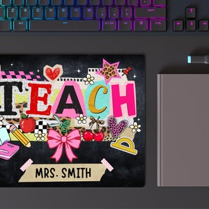 May include: A black mousepad with the word "TEACH" in colorful letters, decorated with school-themed illustrations like an apple, scissors, and a pink bow. The name "MRS. SMITH" is also displayed.