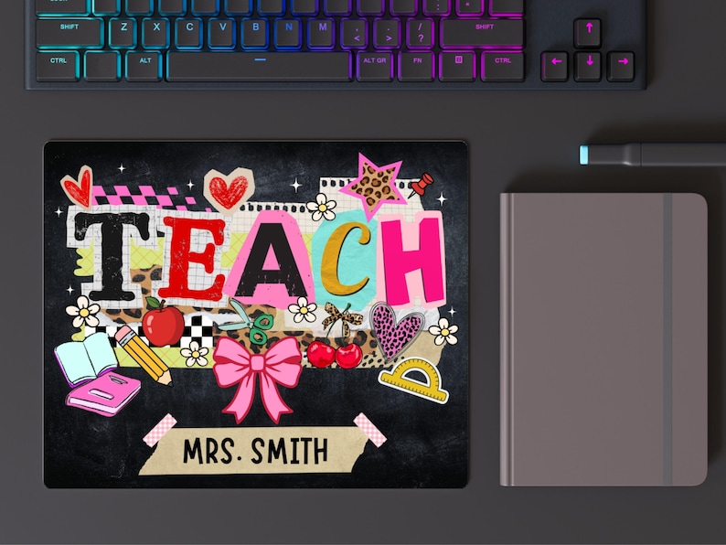 May include: A black mousepad with the word "TEACH" in colorful letters, decorated with school-themed illustrations like an apple, scissors, and a pink bow. The name "MRS. SMITH" is also displayed.