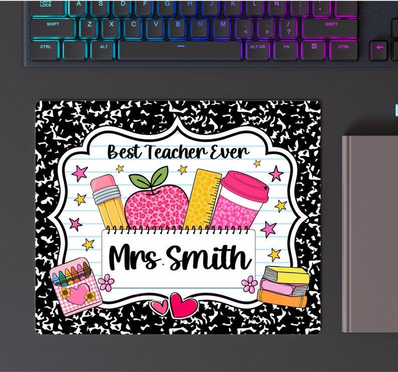 May include: A rectangular mouse pad with a black and white composition notebook pattern border. The center features a white label with the text Best Teacher Ever and Mrs. Smith, decorated with a pencil, leopard print apple, ruler, coffee cup, and crayons.