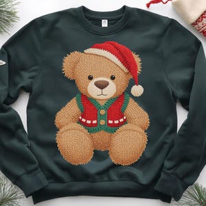 May include: Dark green sweatshirt featuring a knitted teddy bear wearing a red and white Santa hat and a red and green vest. The bear has a brown nose and is centered on the shirt. Christmas-themed apparel.