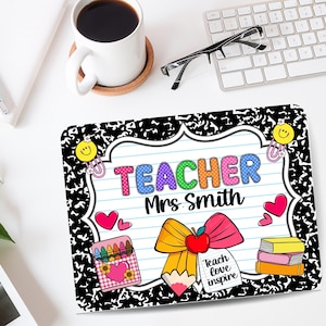 May include: A rectangular mousepad with a black and white notebook paper design. The mousepad features the word "TEACHER" in colorful letters, the name "Mrs. Smith", and school-themed illustrations like a pencil, apple, and books.