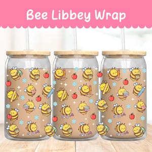 Puede incluir: Tres vasos de cristal transparente con tapas de bambú y pajitas, con un patrón repetitivo de abejas de dibujos animados con material escolar como lápices, libros y manzanas, además de pequeñas flores azules y estrellas blancas.