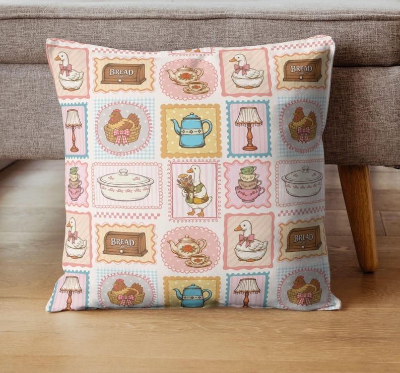 May include: A square throw pillow featuring a repeating grid pattern of illustrations including white geese with pink bows, blue teapots, brown bread boxes labeled BREAD, lamps, chickens in baskets, stacked teacups, and covered casserole dishes.