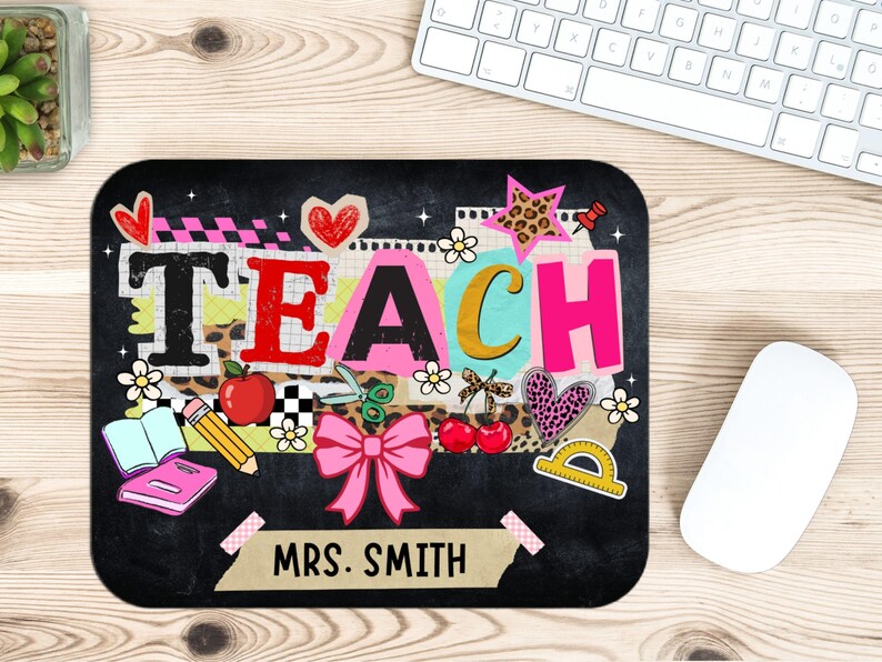 May include: Black mousepad with the word "TEACH" in colorful letters and teacher-themed graphics. Includes a pink bow, apple, pencil, and the name "MRS. SMITH". A white mouse and keyboard are in the background.