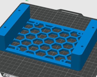 Pode incluir: Um suporte azul brilhante impresso em 3D com uma base retangular central apresentando um padrão de grade hexagonal repetitivo. A estrutura inclui duas paredes laterais sólidas e elevadas, cada uma com dois orifícios de montagem circulares.