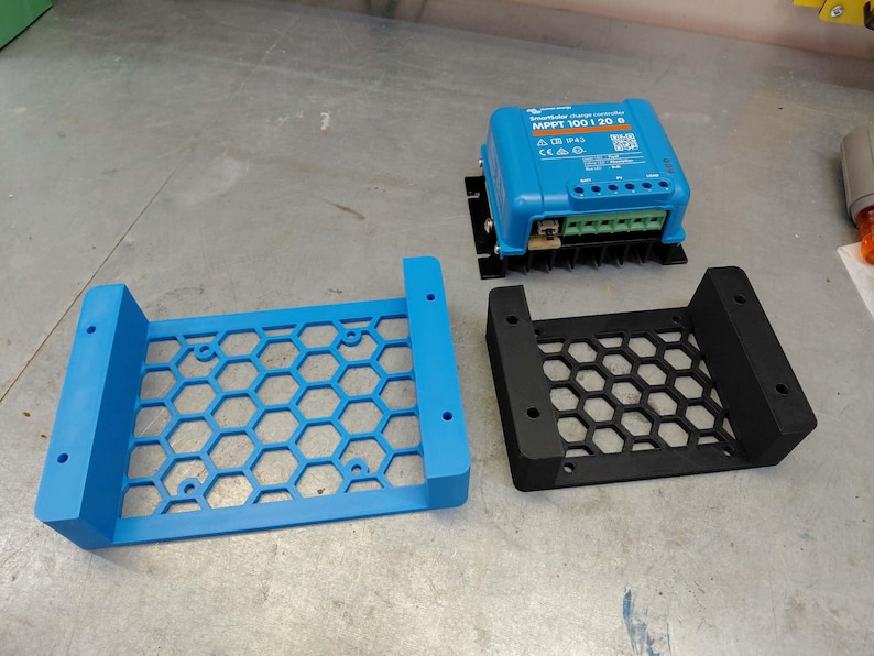 May include: A blue solar charge controller with the text "MPPT 100|20 B" and two honeycomb-patterned mounting brackets, one blue and one black. The controller has multiple connection ports and a QR code.