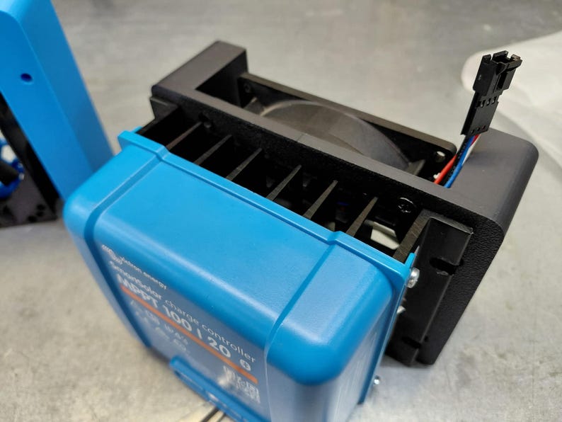 May include: A blue solar charge controller with black cooling fan attached. The controller has the text "MPPT 100/20" printed on it. The fan is black and has a wire connector with red, white, and blue wires.