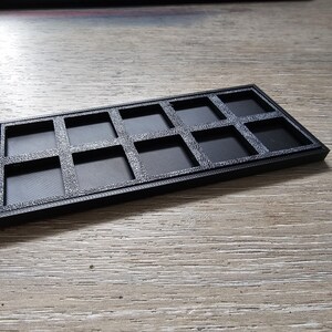 May include: Black plastic storage case with 12 square compartments.