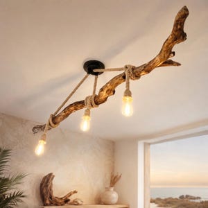 May include: A ceiling light fixture featuring a natural brown driftwood branch suspended by a black circular mount. Three light bulbs hang from the branch, each wrapped in thick beige rope cord, providing warm illumination to the room below.