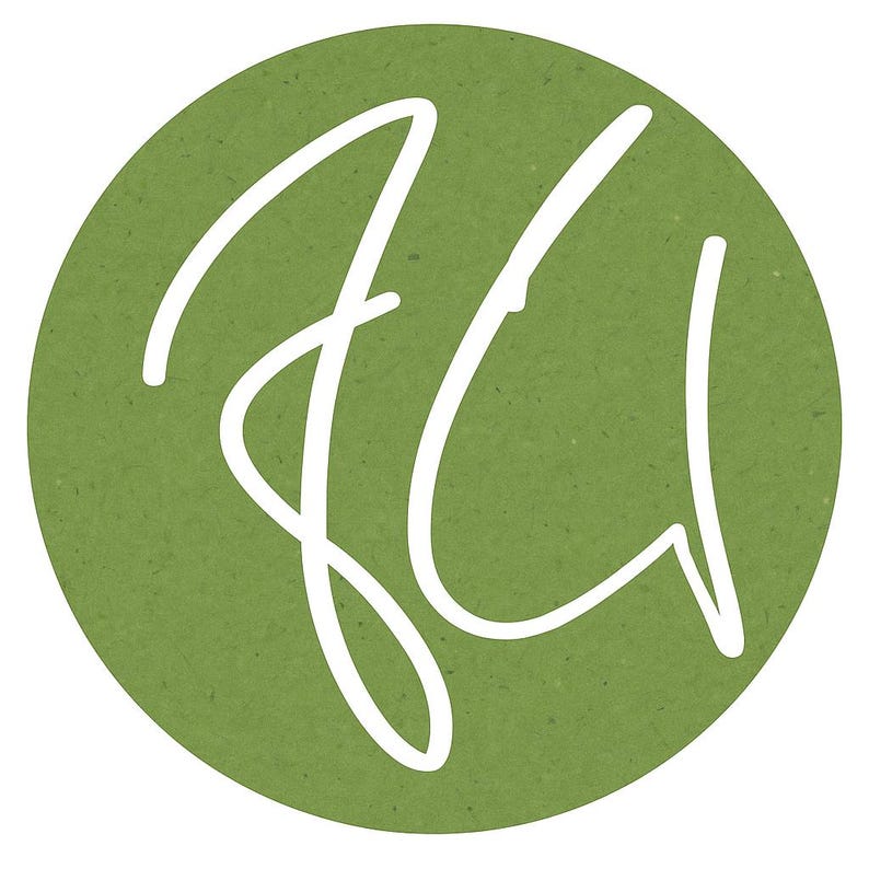 May include: A circular emblem featuring a solid olive green background with a textured, paper-like appearance. Centered on the circle is a stylised, white handwritten monogram consisting of the letters J and U, rendered in a fluid, continuous line.