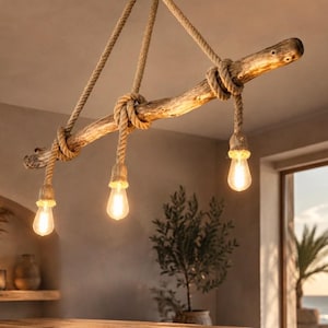 May include: A hanging light fixture featuring a natural wooden branch suspended by thick tan rope. Three light bulbs hang from the branch, each wrapped in matching rope. The bulbs emit a warm, glowing light, creating a soft illumination.