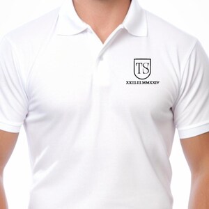 Może przedstawiać: Biała koszulka polo z czarnym haftowanym logo przedstawiającym litery "TS" w kształcie tarczy. Tekst "XXIIIIII MMXXXIV" znajduje się pod logo.