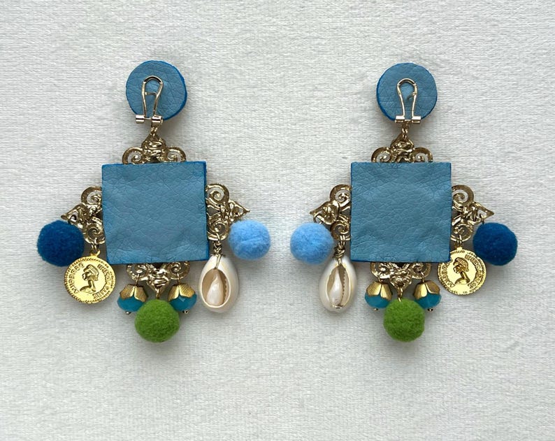 May include: A pair of blue and gold statement earrings with a square blue leather center, gold accents, and blue, green, and white beads.