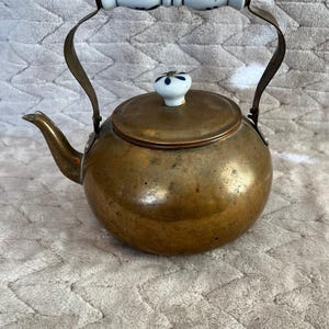 May include: A white ceramic mug with a black handle and the text "But First, Coffee" in a bold, black font. The mug is set against a blurred background, suggesting a cozy setting.