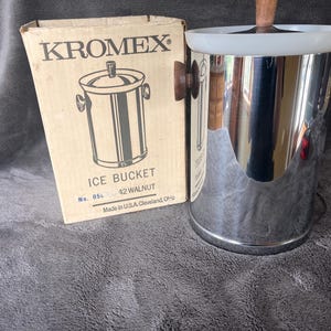 May include: A vintage chrome ice bucket with walnut handles and a white rim, next to its original cardboard box. The box features a line drawing of the ice bucket and the text "KROMEX ICE BUCKET 42 WALNUT". Made in USA.