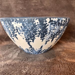 May include: A wide, deep bowl featuring a matte finish with a high-contrast, mottled pattern of dark navy blue and off-white. The exterior surface displays an organic, sponge-painted aesthetic that covers the entire rounded body of the vessel.