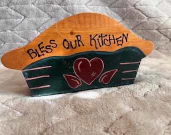 vintage, hand-painted wooden recipe holder featuring a rustic "Bless Our Kitchen" theme