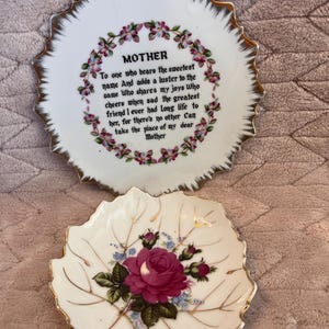 May include: Two decorative porcelain dishes. The top dish is round with a scalloped gold rim and the word "MOTHER" with a poem. The bottom dish is leaf-shaped, featuring a red rose and gold trim.