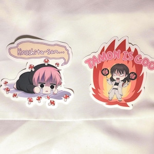 May include: A white ceramic mug with a black handle and the text "But First, Coffee" in a black, handwritten-style font. The mug is on a white surface.