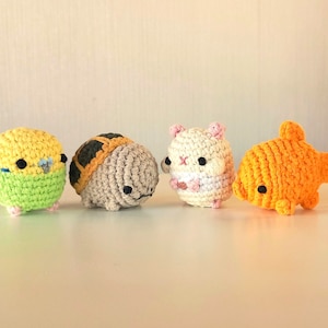 May include: Four crocheted stuffed toys: a yellow and green bird, a brown and tan turtle, a white hamster, and an orange goldfish.