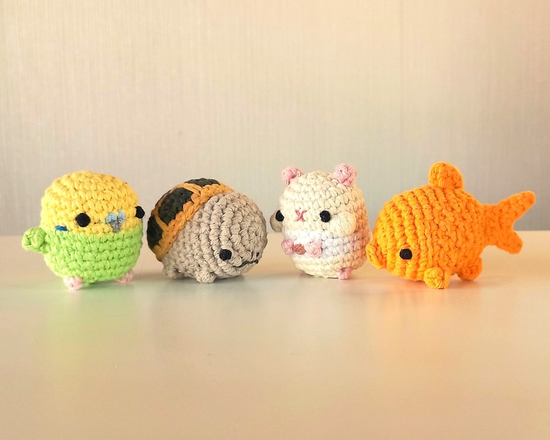May include: Four crocheted stuffed toys: a yellow and green bird, a brown and tan turtle, a white hamster, and an orange goldfish.