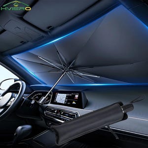 Könnte beinhalten: Ein schwarzer Sonnenschirm für das Auto ist in einem Fahrzeug ausgeklappt. Der Schirm ist geöffnet und spendet Schatten vor der Sonne. Der Innenraum des Autos ist sichtbar, einschließlich Armaturenbrett, Lenkrad und Infotainment-Bildschirm. Der Schirm ist kompakt und faltbar.