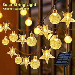 May include: Solar string lights with star and globe-shaped bulbs. The lights are warm yellow and strung on a dark wire. A small solar panel is visible in the image. The text "Solar String Light Outdoor/Waterproof" is at the top.