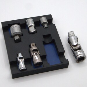 May include: A set of six silver socket adapters in a black foam tray with a blue insert. The adapters are arranged in the tray and one is sitting outside the tray.