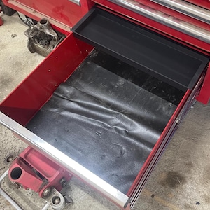 May include: Red metal toolbox drawer with a black rubber mat lining the bottom. The drawer has a silver trim around the edge.