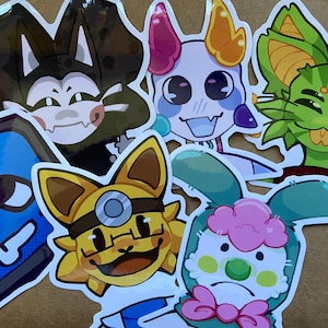 May include: A white ceramic mug with a black handle and the text "But First, Coffee" in a bold, black font. The mug is set against a blurred background, suggesting a cozy setting.