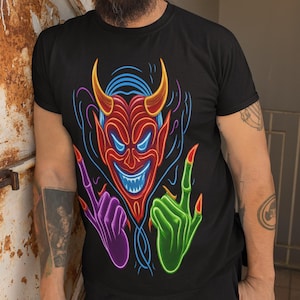 May include: Black t-shirt featuring a neon devil graphic. The devil has red skin, yellow horns, and a blue outline. The graphic includes purple and green hands with red fingernails. The shirt is a crew neck.