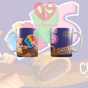 Puede incluir: Una taza de cerámica de color morado y azul con un asa blanca. La taza presenta un diseño de caja de cereal colorido con el texto "Flapjacks" y "Chocolate". El diseño de la caja de cereal incluye una imagen del cereal y un panel de información nutricional.