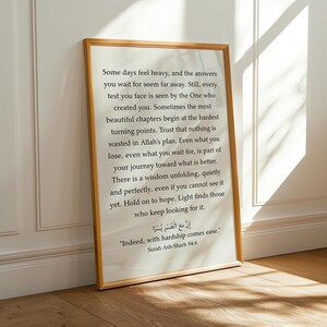 May include: A rectangular wall art print in a thin light wood frame featuring black printed text on a white background. The text includes an inspirational message about faith and patience, followed by the Arabic script and English translation of Surah Ash-Sharh 94:6, "Indeed, with hardship comes ease."