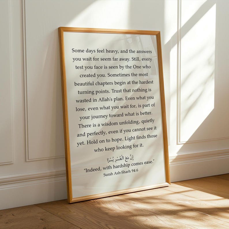 May include: A rectangular wall art print in a thin light wood frame featuring black printed text on a white background. The text includes an inspirational message about faith and patience, followed by the Arabic script and English translation of Surah Ash-Sharh 94:6, "Indeed, with hardship comes ease."