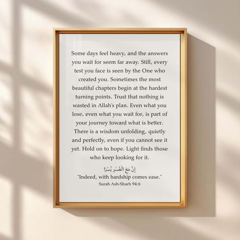May include: A framed wall art print featuring black text on a white background. The text reads: Some days feel heavy, and the answers you wait for seem far away. It includes the Arabic script and the English translation: Indeed, with hardship comes ease. Surah Ash-Sharh 94:6.