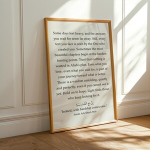 May include: A rectangular wall art print in a light wood frame featuring black text on a white background. The text includes an inspirational message about hope and faith, followed by the Arabic script and English translation of Surah Ash-Sharh 94:6.
