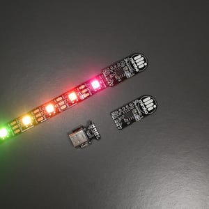 Peut inclure: Une bande LED flexible avec des lumières multicolores, passant du vert au rouge. La bande est connectée à une petite carte de circuit imprimé et à un connecteur USB. Image de composants électroniques.