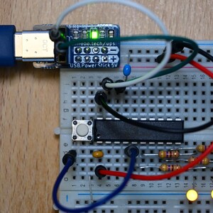 May include: A close-up of an electronics project on a breadboard. A blue USB cable from IKEA is connected to a small circuit board labeled "USB Power Stick 5V". Various wires, resistors, and LEDs are connected, with some LEDs illuminated.