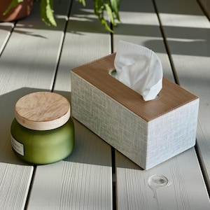 Rectangular PU leather tissue box cover with linen‑style beige texture and stitched wooden top, designed to fit standard Kleenex rectangular boxes. Features a modern, minimalist look that blends seamlessly with home décor styles from contemporary to boho. Durable magnetic closure allows easy tissue replacement, while the elegant design makes it perfect for bathroom, bedroom, living room, or office use. A stylish and functional home accessory or thoughtful gift idea.