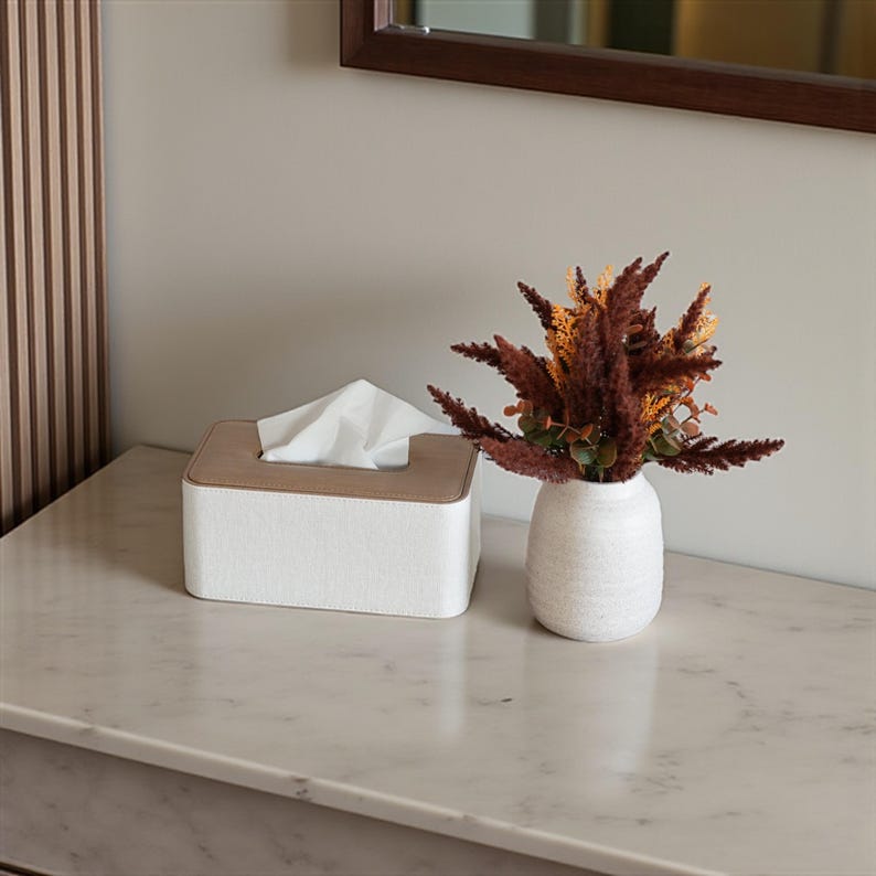 Rectangular PU leather tissue box cover with linen‑style beige texture and stitched wooden top, designed to fit standard Kleenex rectangular boxes. Features a modern, minimalist look that blends seamlessly with home décor styles from contemporary to boho. Durable magnetic closure allows easy tissue replacement, while the elegant design makes it perfect for bathroom, bedroom, living room, or office use. A stylish and functional home accessory or thoughtful gift idea.