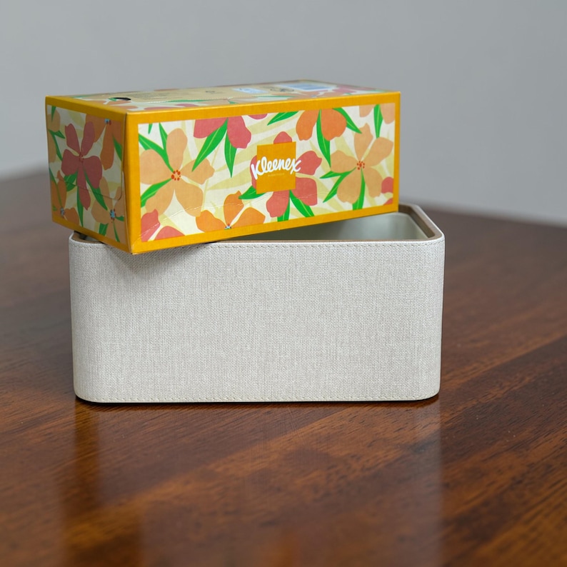 Rectangular PU leather tissue box cover with linen‑style beige texture and stitched wooden top, designed to fit standard Kleenex rectangular boxes. Features a modern, minimalist look that blends seamlessly with home décor styles from contemporary to boho. Durable magnetic closure allows easy tissue replacement, while the elegant design makes it perfect for bathroom, bedroom, living room, or office use. A stylish and functional home accessory or thoughtful gift idea.
