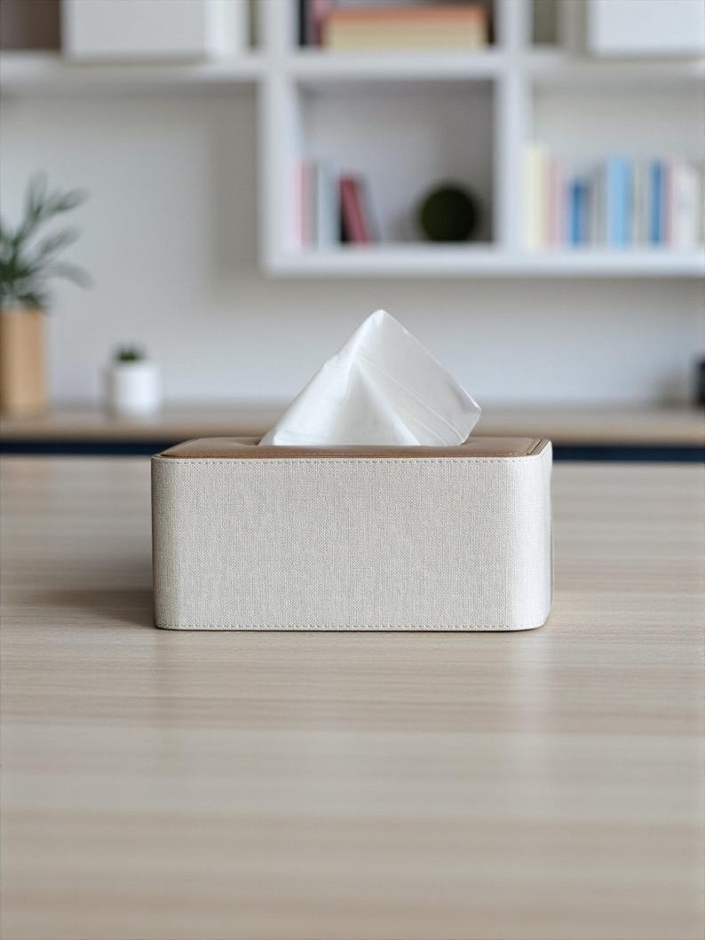 Rectangular PU leather tissue box cover with linen‑style beige texture and stitched wooden top, designed to fit standard Kleenex rectangular boxes. Features a modern, minimalist look that blends seamlessly with home décor styles from contemporary to boho. Durable magnetic closure allows easy tissue replacement, while the elegant design makes it perfect for bathroom, bedroom, living room, or office use. A stylish and functional home accessory or thoughtful gift idea.